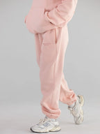 Close-up view of pink sweatpants with cuffed ankles and side pockets.