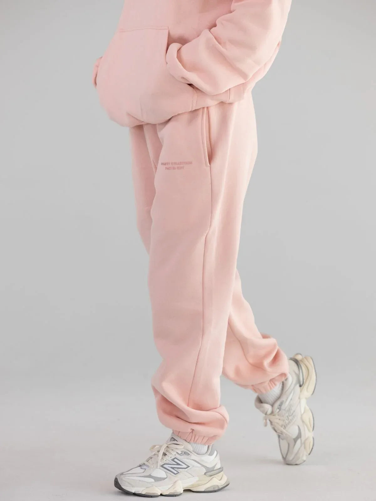 Close-up view of pink sweatpants with cuffed ankles and side pockets.