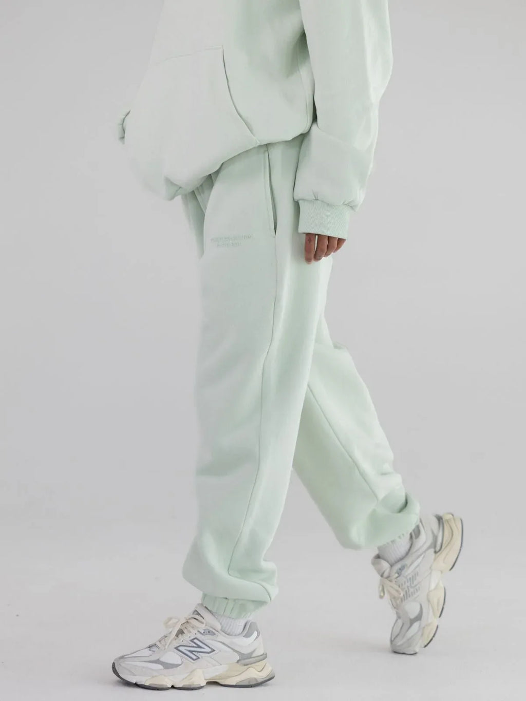 Person wearing a mint green hoodie and sweatpants set with sneakers.