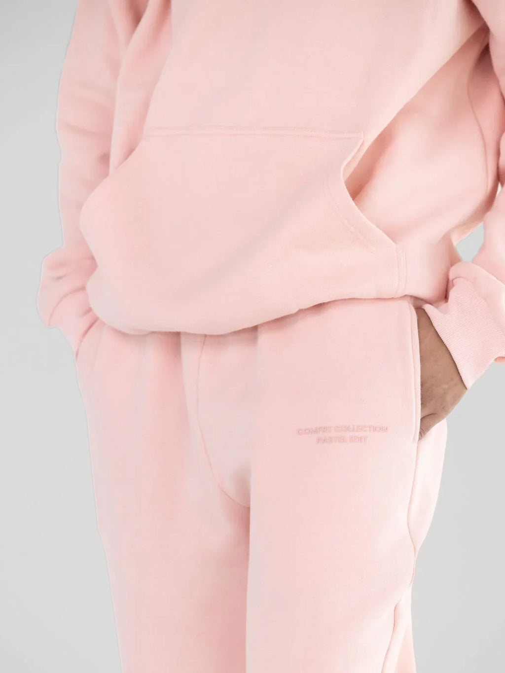 Detail shot of pink sweatpants showing embroidered logo and pocket.