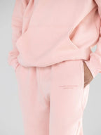 Detail shot of pink sweatpants showing embroidered logo and pocket.