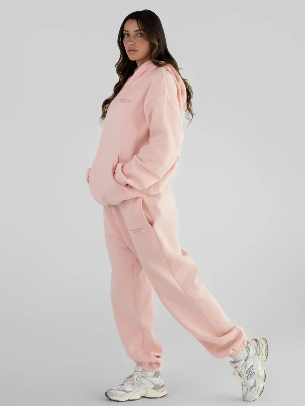 Woman wearing a pink hoodie and sweatpants set.