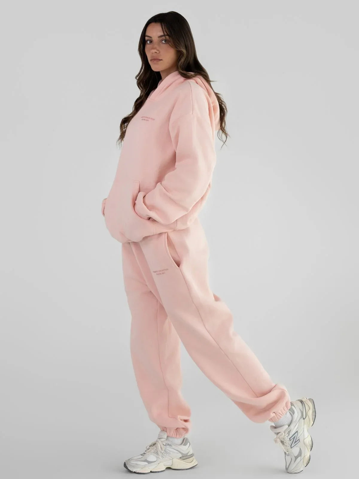 Woman wearing a pink hoodie and sweatpants set.