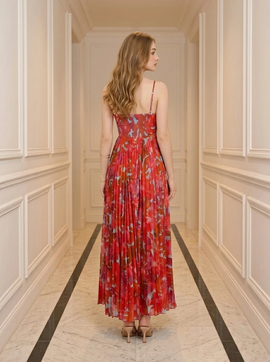 Woman standing in a hallway wearing a red floral print midi dress with pleats and cami straps.