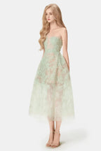 Woman in a mint green strapless lace dress with a full skirt