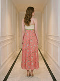 Rear view of a woman in a coral midi dress with a white bodice and a patterned skirt.