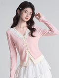 Woman in a pink cardigan and white layered top, showcasing the neckline.