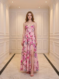 Woman wearing a pink floral print maxi dress with spaghetti straps and a thigh-high slit.