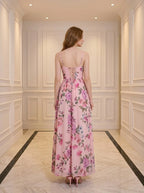 Back view of a woman in a pink floral print maxi dress with a lace-up back detail.