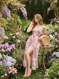 Woman posing in a pink floral print maxi dress with a thigh-high slit in a garden setting.