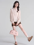 Full body shot of a woman wearing a pink peplum blouse, brown skirt, and sneakers.