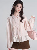 Woman wearing a pink long-sleeved peplum blouse with pintuck detailing and a ruffled lace hem.