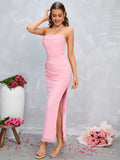 Woman adjusting her hair while wearing a pink strapless ruched maxi dress