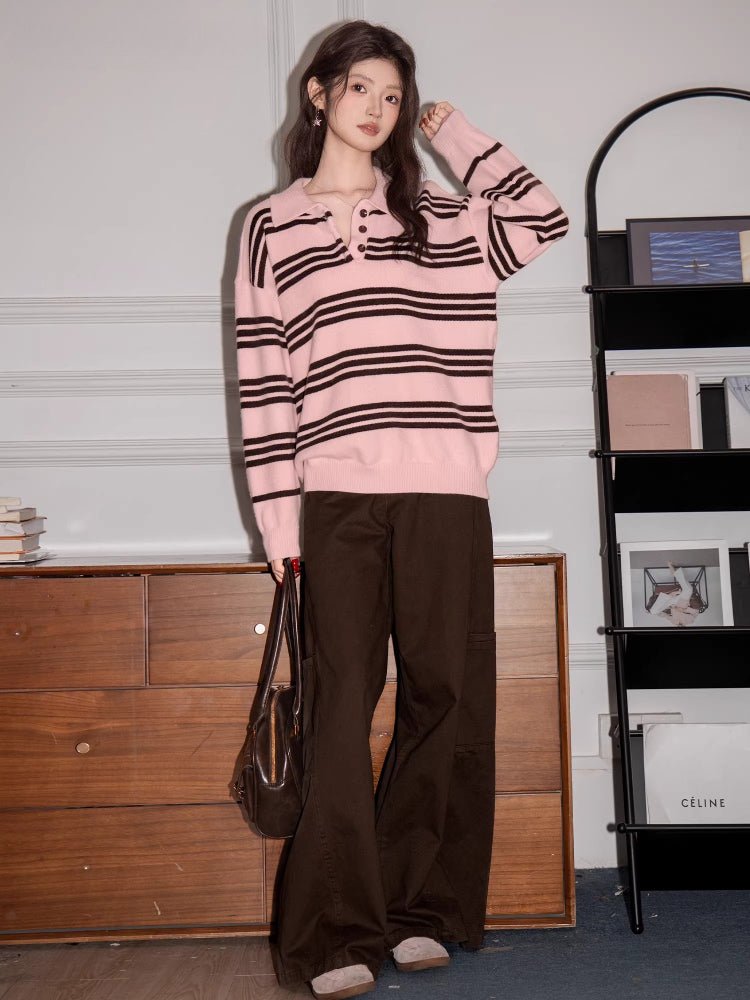 Full body shot of a woman in a pink and brown striped polo sweater and brown pants