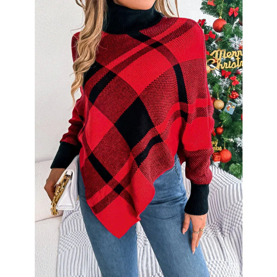 Woman holding a white clutch while wearing a red and black plaid turtleneck poncho sweater