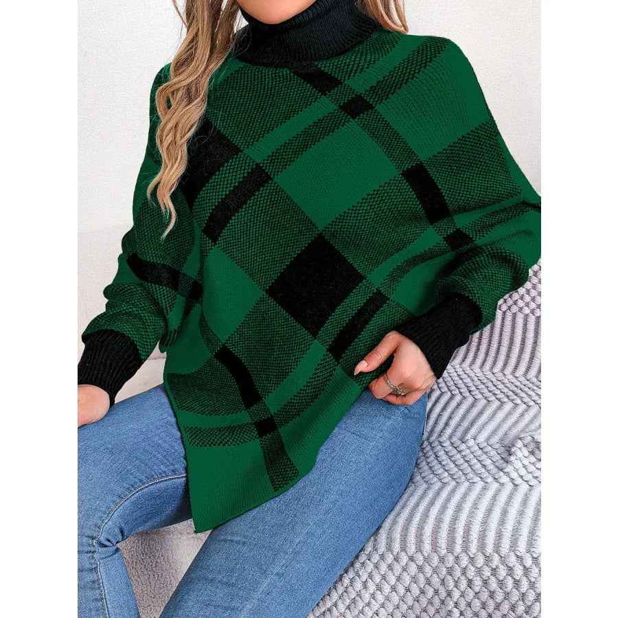 Woman wearing a green and black plaid turtleneck poncho sweater with blue jeans