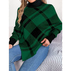 Woman wearing a green and black plaid turtleneck poncho sweater with blue jeans