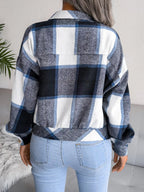 Back view of a woman wearing a blue, black, and white plaid flannel shirt jacket.