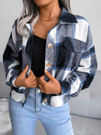 Front view of a woman in a plaid shirt jacket, hands near the buttons.