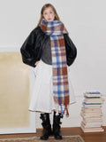 Full body shot of a woman wearing a plaid scarf, black jacket, and white skirt.