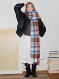 Woman posing with a plaid scarf and black jacket.