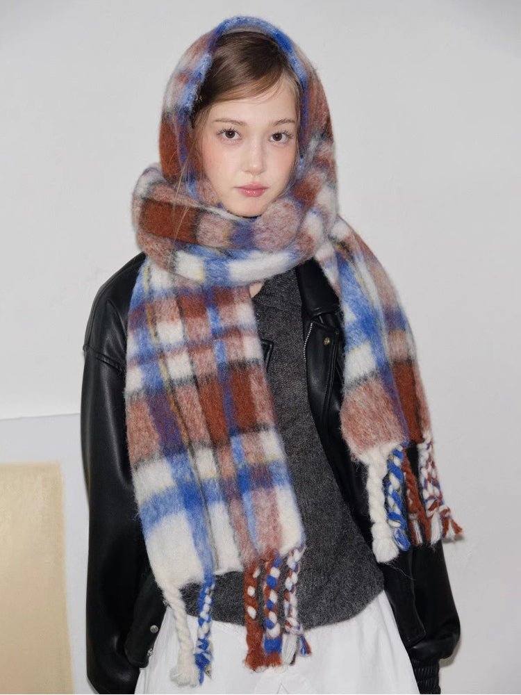 Model wearing a plaid scarf with tassels draped around her neck.