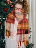 Full-body shot of a model with a large plaid scarf draped around her neck.