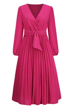 Front view of a pink long-sleeved midi wrap dress with accordion pleats and a belt.