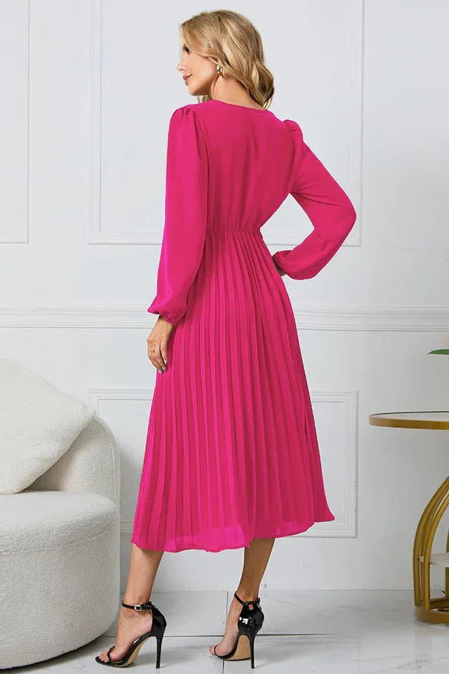 Back view of a woman wearing a long-sleeved pink pleated midi dress.