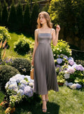 Woman wearing a gray satin midi dress with spaghetti straps and a square neckline, posing in a garden with hydrangeas.