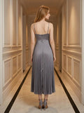Back view of a woman wearing a gray satin midi dress with spaghetti straps and a square neckline, standing in a hallway.