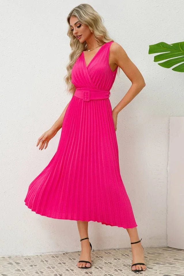 Woman twirling in a vibrant pink pleated midi dress, highlighting the skirt's flow.
