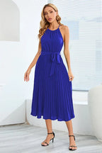 Front view of a royal blue pleated halter neck midi dress with a self-tie belt