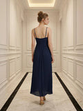 Back view of a woman in a navy blue pleated maxi dress with a halter neckline.
