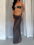 Woman wearing a black and white polka dot strapless bikini and a matching sheer maxi skirt, front view.