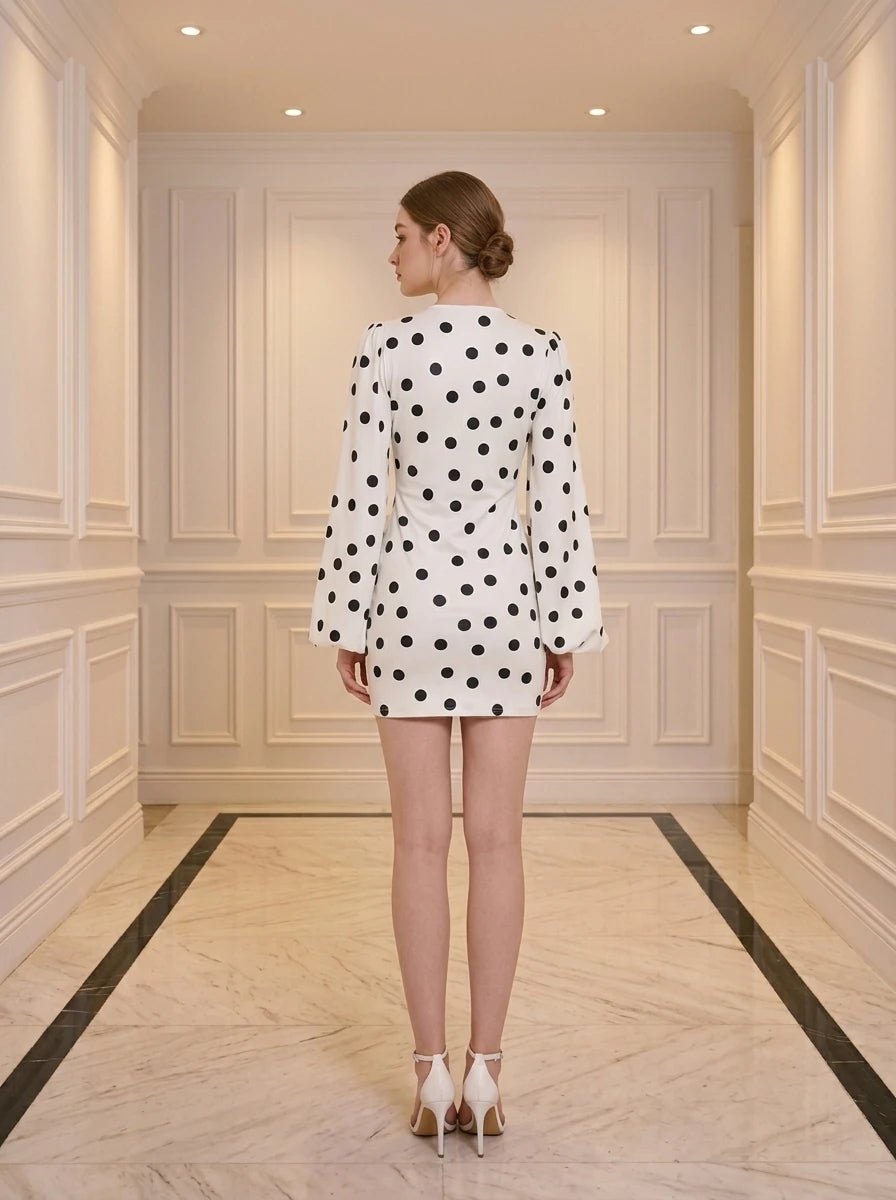 Back view of a woman in a white polka dot mini dress with plunging V-neck and bishop sleeves
