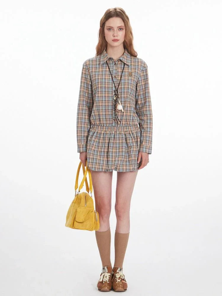 Woman wearing a plaid collared shirt dress with an elasticated waist and long sleeves, holding a yellow handbag.