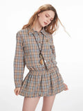 Woman posing in a plaid collared shirt dress with an elasticated waist and long sleeves.