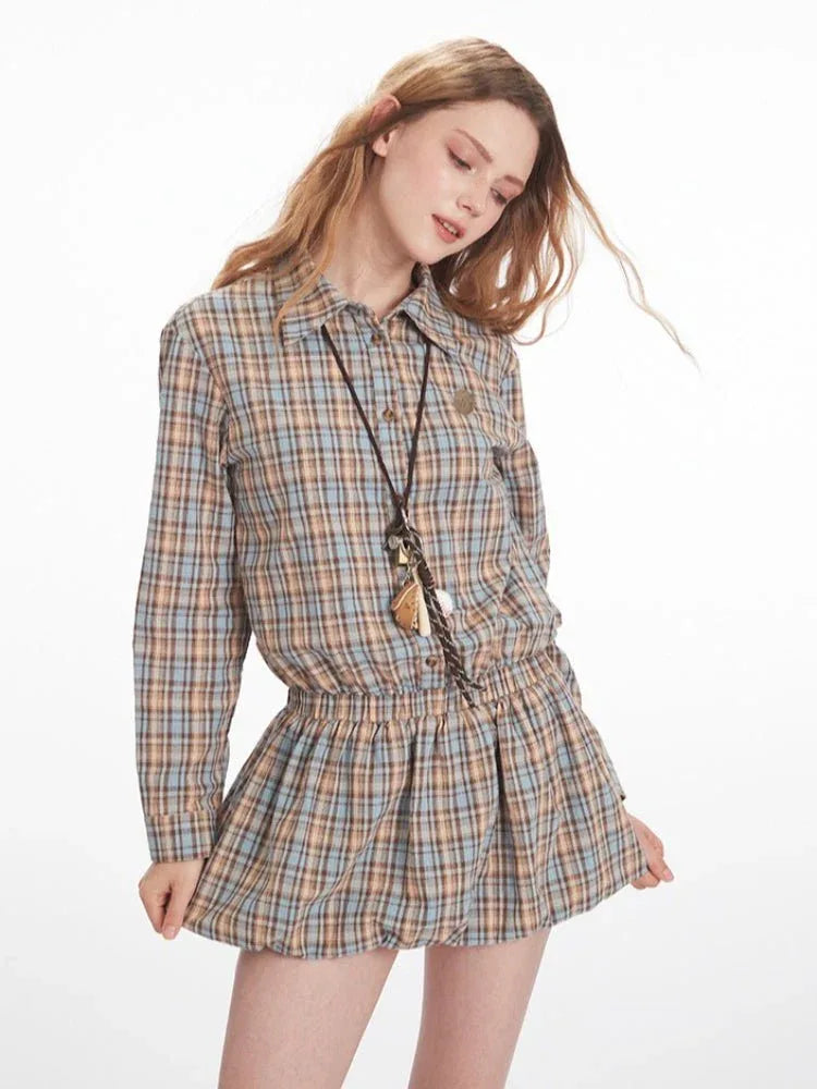 Woman posing in a plaid collared shirt dress with an elasticated waist and long sleeves.