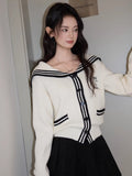 A woman poses in a cream knit cardigan with navy sailor collar and trim, showcasing the garment's silhouette.