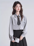 Model posing with a grey pinstripe blouse and a dark grey tie