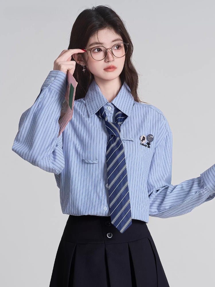 Woman adjusting her glasses while wearing a light blue striped shirt and navy tie