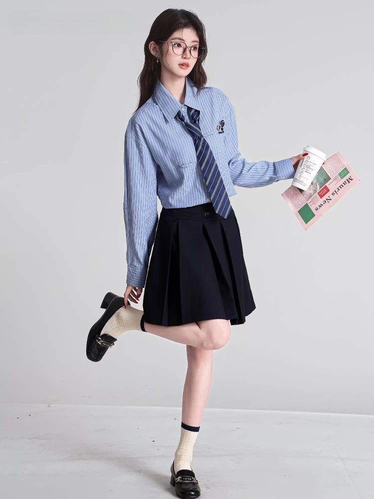 Woman holding a coffee cup and a folded newspaper while wearing a light blue striped shirt and navy tie
