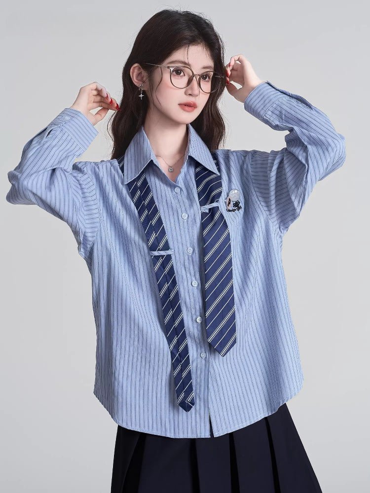 Woman wearing a light blue striped button-down shirt with a navy tie and glasses