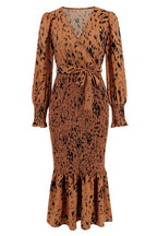 product shot of a brown and black leopard print long sleeve smocked midi dress with a tie waist and ruffled hem