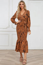 woman posing in a brown and black leopard print long sleeve smocked midi dress with a tie waist