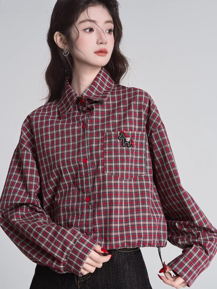 Woman wearing a red and beige plaid cropped shirt with a collared neckline and long sleeves.