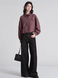 Full body shot of a woman wearing a red and beige plaid cropped shirt with wide-leg black jeans and a black handbag.