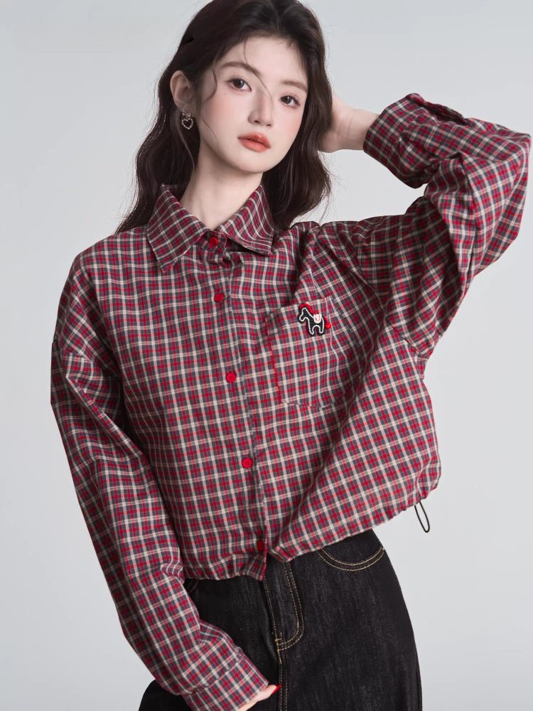 Woman wearing a red and beige plaid cropped shirt with a collared neckline and long sleeves.