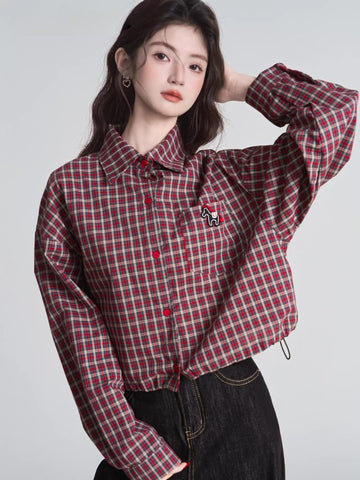 Woman wearing a red and beige plaid cropped shirt with a collared neckline and long sleeves.